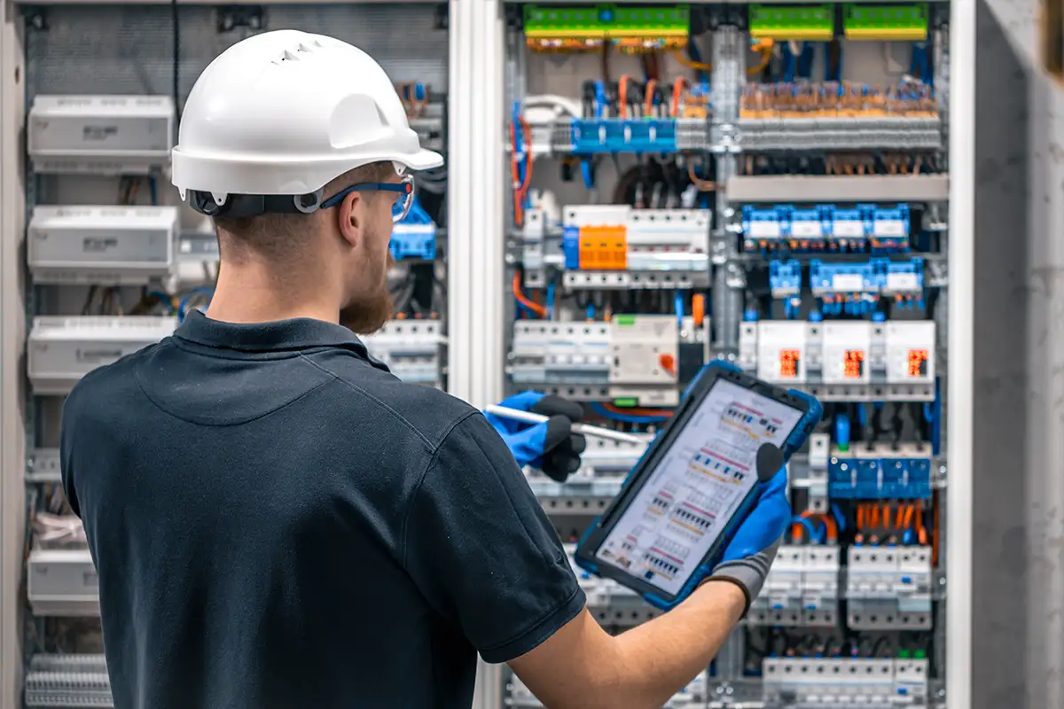Elektriker mit Tablet beim Einstellen der Schaltkreise an der Anschlussdose