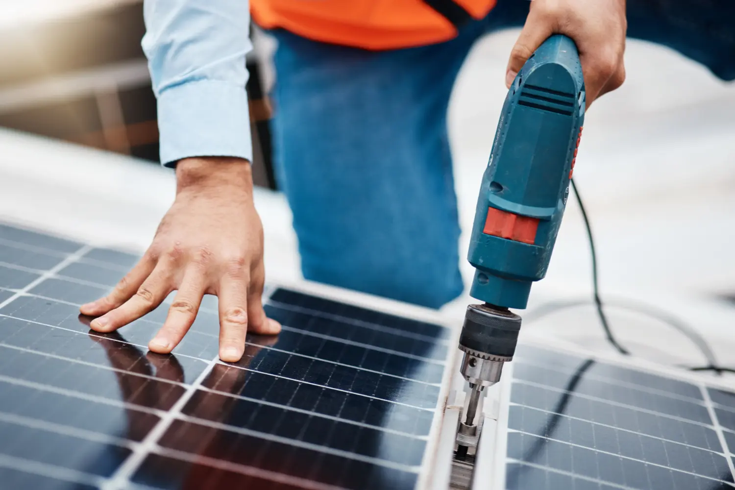 Techniker befestigt Solarpanel mit Bohrmaschine bei der Photovoltaik-Montage auf dem Dach