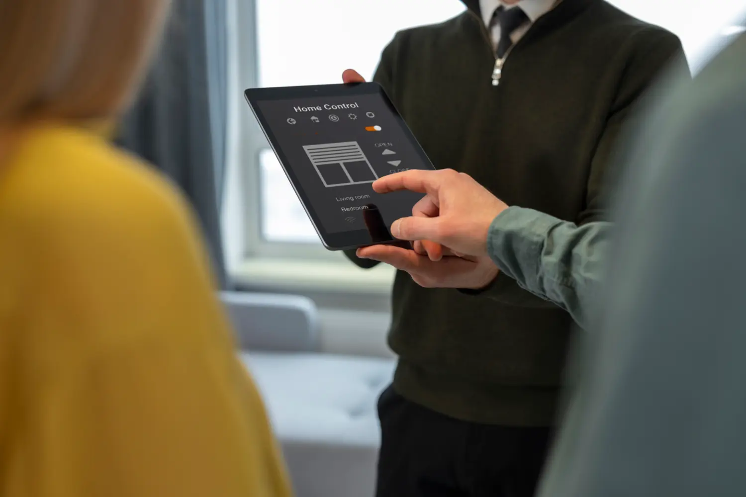 Berater zeigt Paar die Smart-Home-Steuerung für Beschattung und Raumkontrolle auf einem Tablet